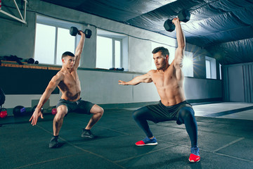 Athletic man doing exercise for arms. Photo of muscular fitness male athletes working out with dumbbells at gym. Healthy lifestyle concept