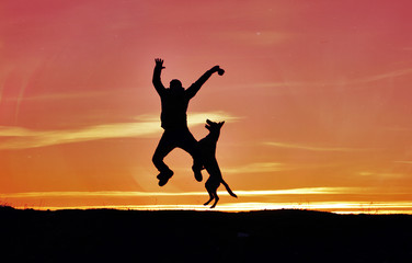 Fototapeta premium Silhouettes of man and dog on sunset background