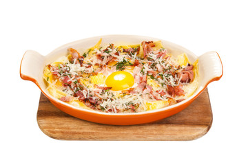 Breakfast. Scrambled eggs with bacon, meat, grated Parmesan cheese, in ceramic ware, on a wooden stand. Isolated on white background
