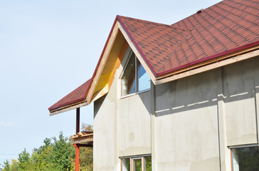 Roofing construction with asphalt shingles in problem areas. Unfinished house plastering and painting walls outdoor.