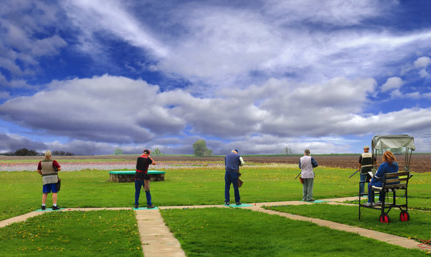 trap shooters under dramatic sky