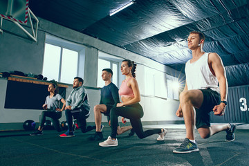 Shot of young men and women at the gym. Functional fitness workout. The group of people during...