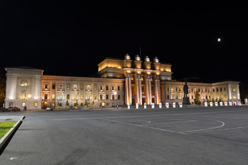 The night picture of beautifully lit opera theater in Samara against the background of the black sky and the moon.