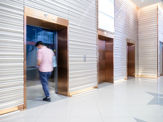 People are walking in office past elevators, Modern steel elevator cabins in a business lobby or...