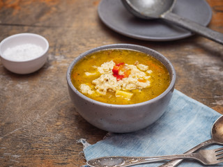 Hot soup with dumplings in a deep plate on a rustic table.