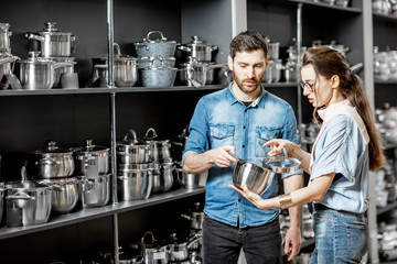 Couple choosing pans for cooking in the shop