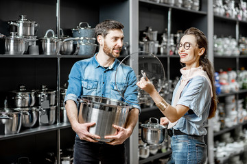 Couple choosing pans for cooking in the shop