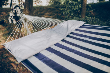 Fototapeta na wymiar Stylish striped hammock hanging outdoors at nature resort close-up, blue and white stipes on comfortable hammock for relaxation, leisure concept
