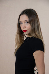 Half-length portrait of a beautiful young blonde woman in a black dress. Girl posing in studio with serious expression, on white background. Perfect makeup with red lips.