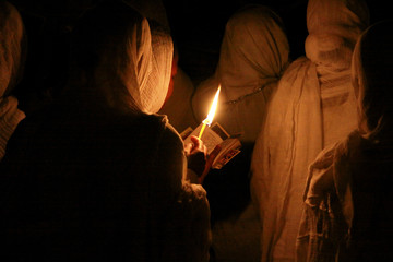 kobieta w chuście modląca się przy świetle świecy w święto trzech króli w etiopii - obrazy, fototapety, plakaty
