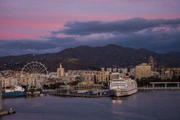 Obraz premium Beautiful sunrise sky in the marina bay of Malaga city. Stunning pink and orange seascape.