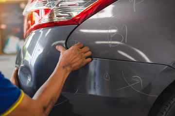 Deurstickers sufferer hand checking of vehicle car bumper dented broken from collision crash damage accident on road,checking cars for scratches and dents © chartphoto