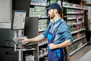 Handsome man working with professional equipment for coloring in the department with paints of the building supermarket