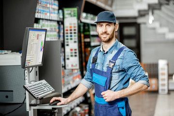 Portrait of a handsome man standing near the professional equipment for coloring in the department with paints of the building supermarket