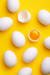 White eggs pattern (broken and whole) on a yellow background viewed from above. Top view