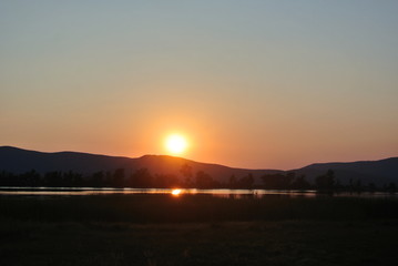 Beautiful sunset on the lake in summer with mountain views