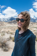 Naklejka premium Portrait of Adult female wearing sunglasses on a windy summer day in the Alabama Hills in Lone Pine California, in the Eastern Sierra Nevada Mountains