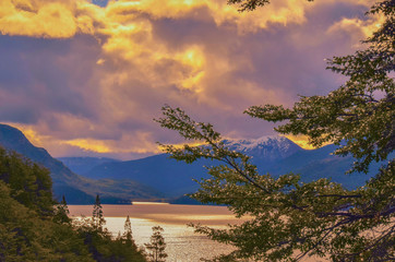 cielo naranja sobre un lago rodeado de bosque y montañas