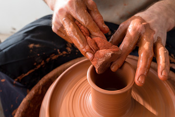 hands of potter creating a jar on circle