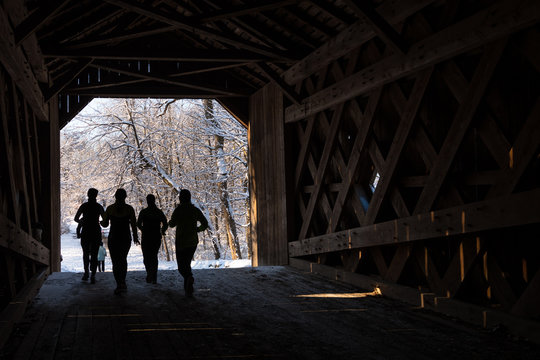 Runners crossing a wooden covered bridge