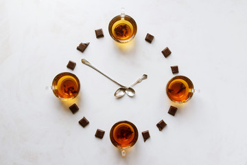 Time to drink tea. Cups of black tea and black chocolate make up the clock.