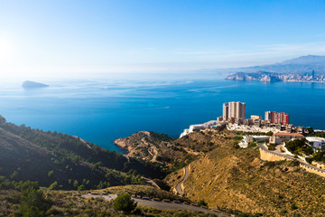 Top view of Benidorm Spain with skyscrapers and mountain roads and the island of Isla on a sunny day