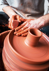 hands of potter creating a jar on circle