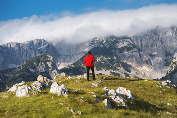 Fototapeta na wymiar Hiker in red jacket enjoying at breathtaking view in mountain