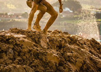 Trail running athlete crossing the dirty puddle in a mud racer.
