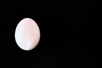 Egg for coloring. One white egg is located on a black background.