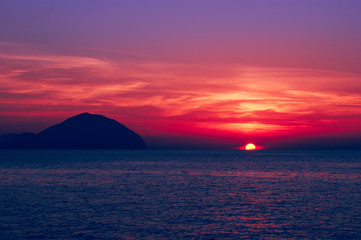Fototapeta na wymiar Beautiful seascape at sunset. Saturated colors, silhouette of a rocky island in the sea.