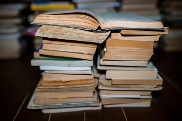 Opened book on columns of books, shallow depth of field, cracked wood floor.