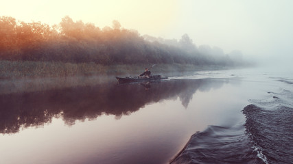 Fisherman swims on a kayak on the river.