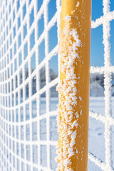 Frozen fence made of metal mesh covered with frost crystals, an early sunny cold morning, on a blurred background