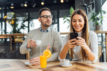 Man looking over his girlfriend shoulder at her phone