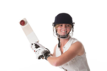 Woman cricketer in a white dress with a safety helmet, shin pads, a bat and ball.