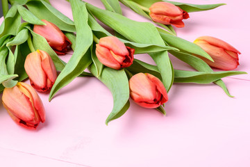 Bouquet of red tulips on pink painted wood background, side view, with space for text, for Valentine's Day or Mother's Day