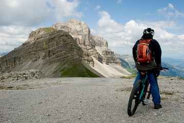 man with electric bike, e-bike, ebike, observes Cima Pietra Grande Peak and Passo Grostè, Dolomites mountains, unesco heritage, Madonna di Campiglio, sport, adventure, travel, Alps, Trentino, Italy