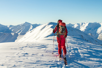 Naklejka premium Male ski tourer enjoying the view on a summit in the alps
