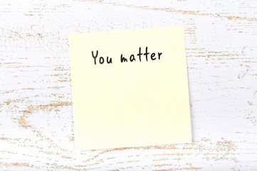 Positive inspiring quote handwritten on sticky note on wooden background