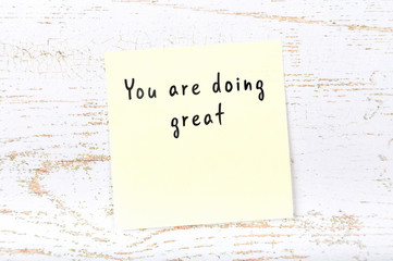 Positive inspiring quote handwritten on sticky note on wooden background