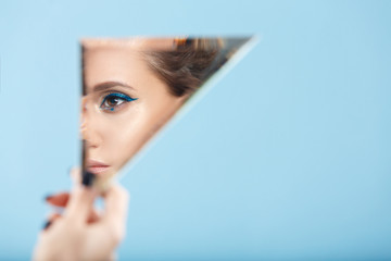 Woman looking at her self reflected in a mirror, selfie, vanity, conceit, ego, digital narcissism concept minimal flat design. An illusion, beautiful girl with a mirror in her hands