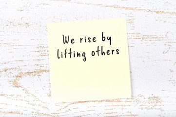 Positive inspiring quote handwritten on sticky note on wooden background