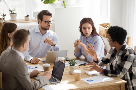 Colleagues listening to african employee telling opinion at group meeting
