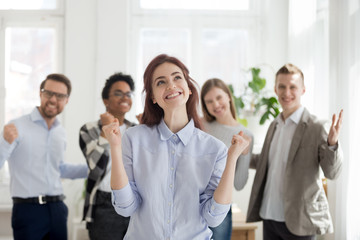Excited employee celebrating business success with happy colleagues at background