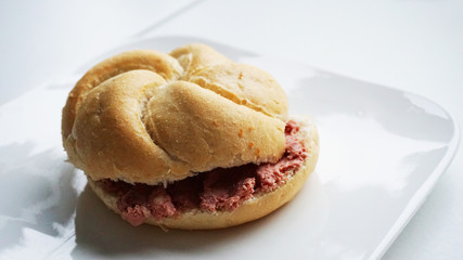 Cut in half bun with pate inside on a white plate on a white background. Picture for a restaurant or cafe menu, for a recipe site or book