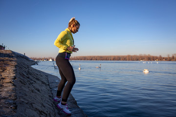 young woman jogging and workout by the river full of swans in city 