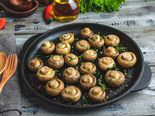 Fried, baked mushrooms in frying pan on wooden table