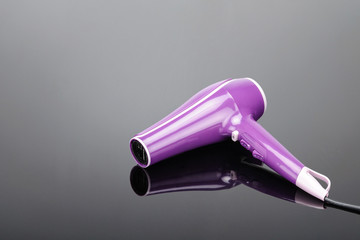 Pink hair dryer on the grey mirror background with copy space