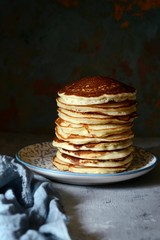 A stack of lush punkcakes for breakfast on a gray background. High pile of delicious pancakes with berries.American Cuisine, Copy space